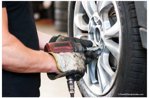 Mechanic tightening lug nuts with an air tool.